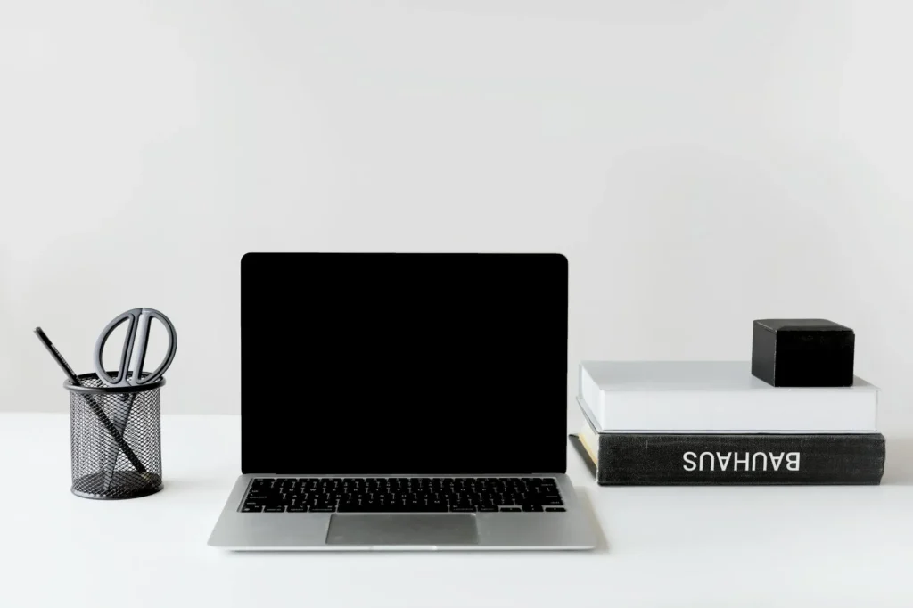 Clean and organized workspace featuring a laptop, books, and pen holder.