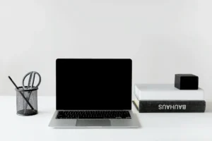 Clean and organized workspace featuring a laptop, books, and pen holder.