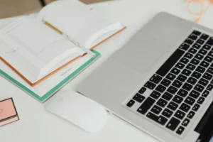 Overhead view of a modern workspace featuring an open planner and laptop on a tidy desk.