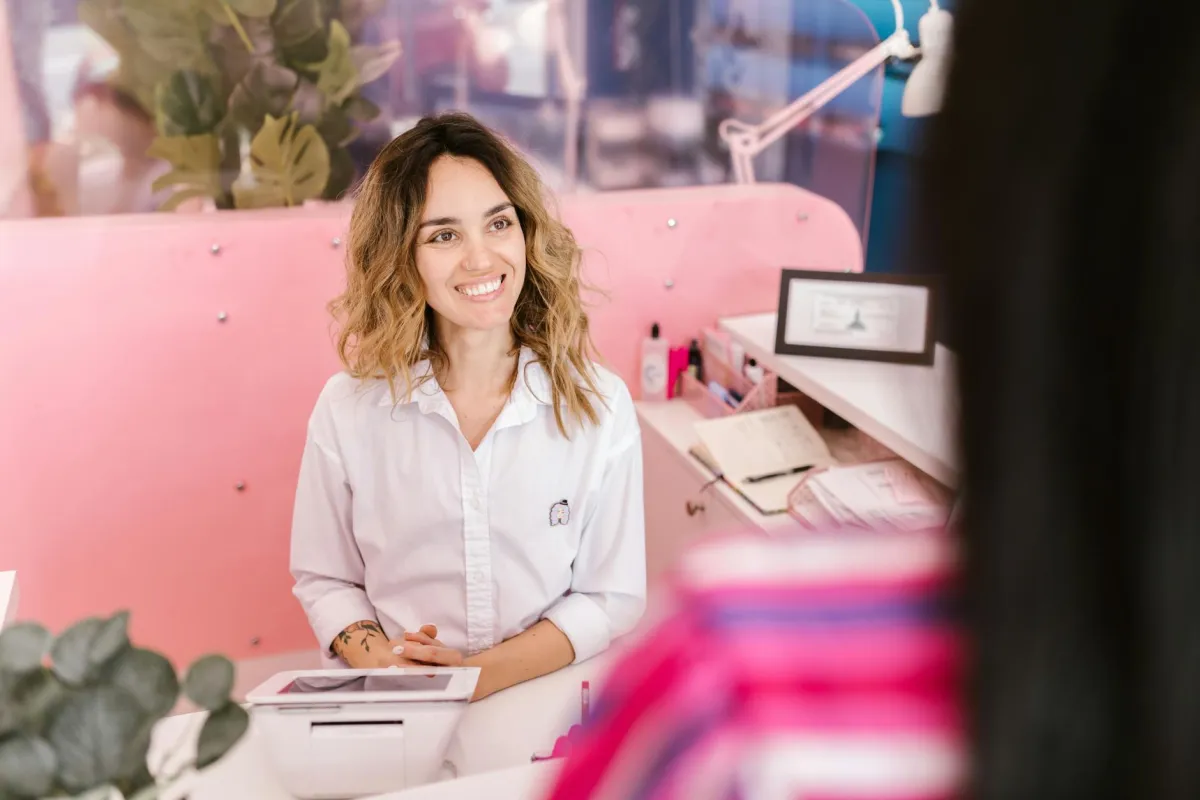 Busy salon receptionist at front desk managing phone calls and walk-in clients on Monday morning
